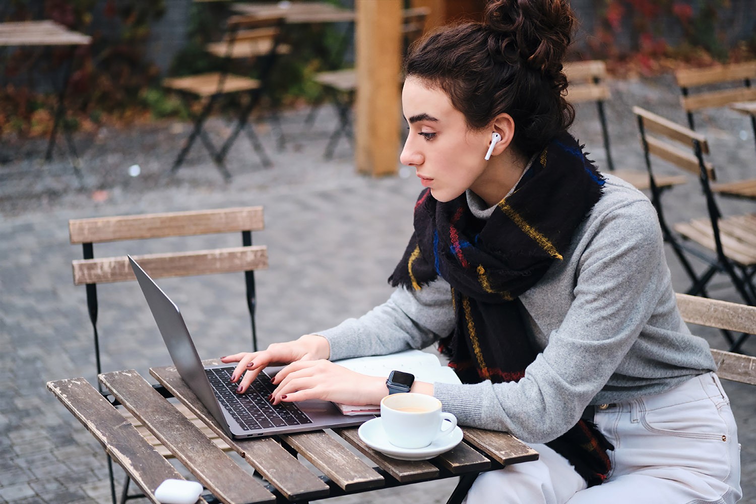 Student sits outside on park table on laptop. 