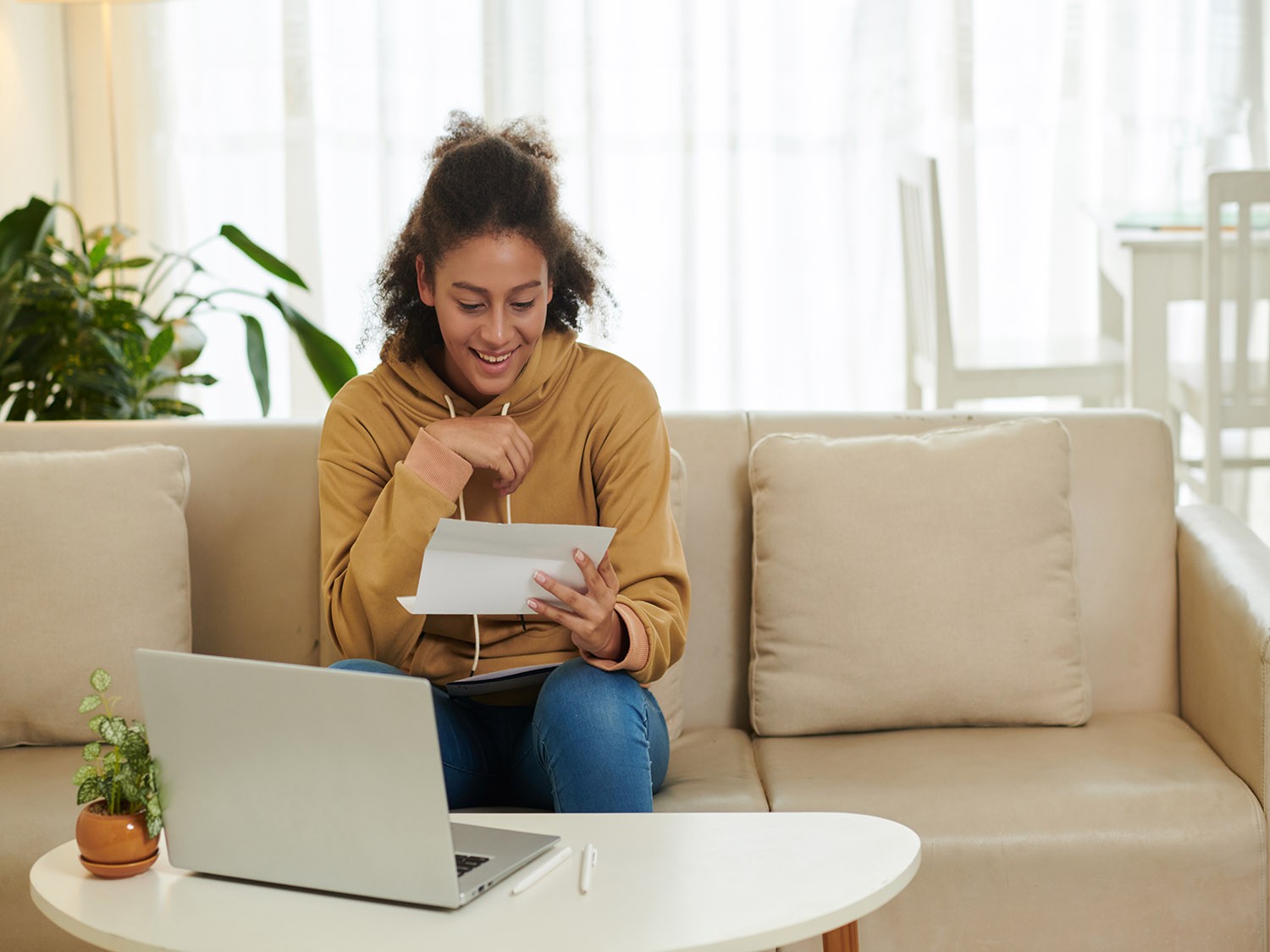 Girl reading over paperwork on couch with laptop