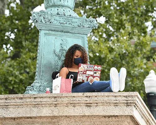 Student sitting outside on campus wearing a mask