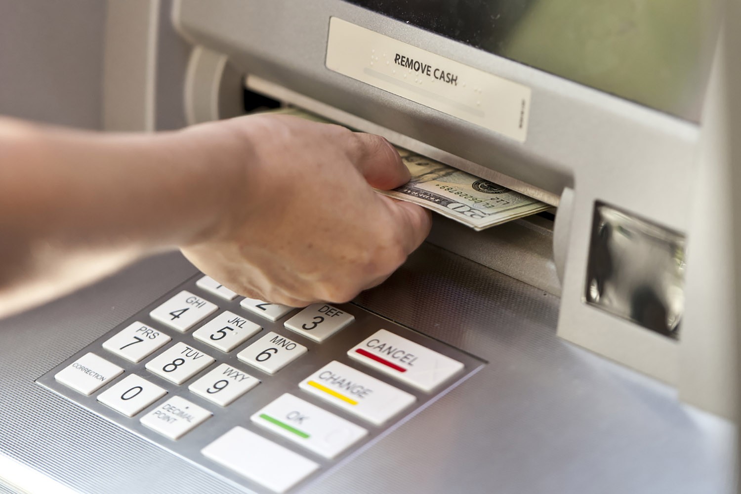Closeup of hand taking out cash from ATM