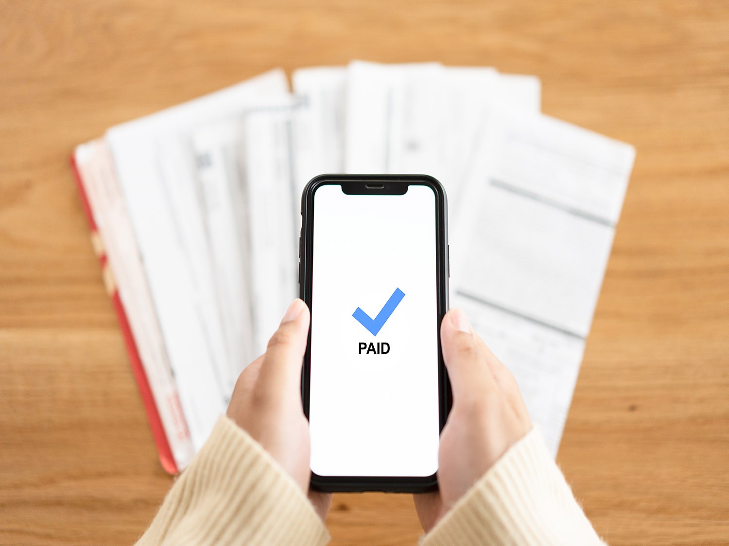 Birds eye view of a smartphone making payments above a stack of papers